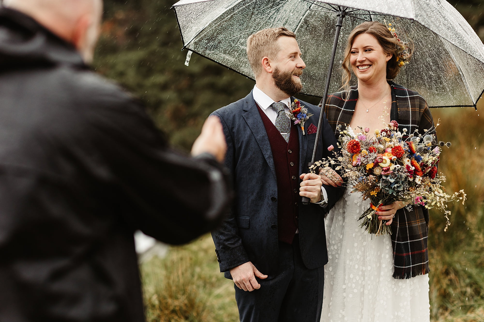monachyle mhor ceremony outside elopement in the rain with umbrella bride and groom tartan blanket