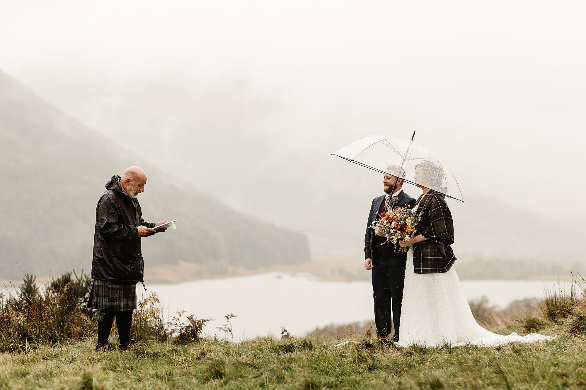 monachyle mhor ceremony outside elopement in the rain with umbrella bride and groom tartan blanket gary the humansit