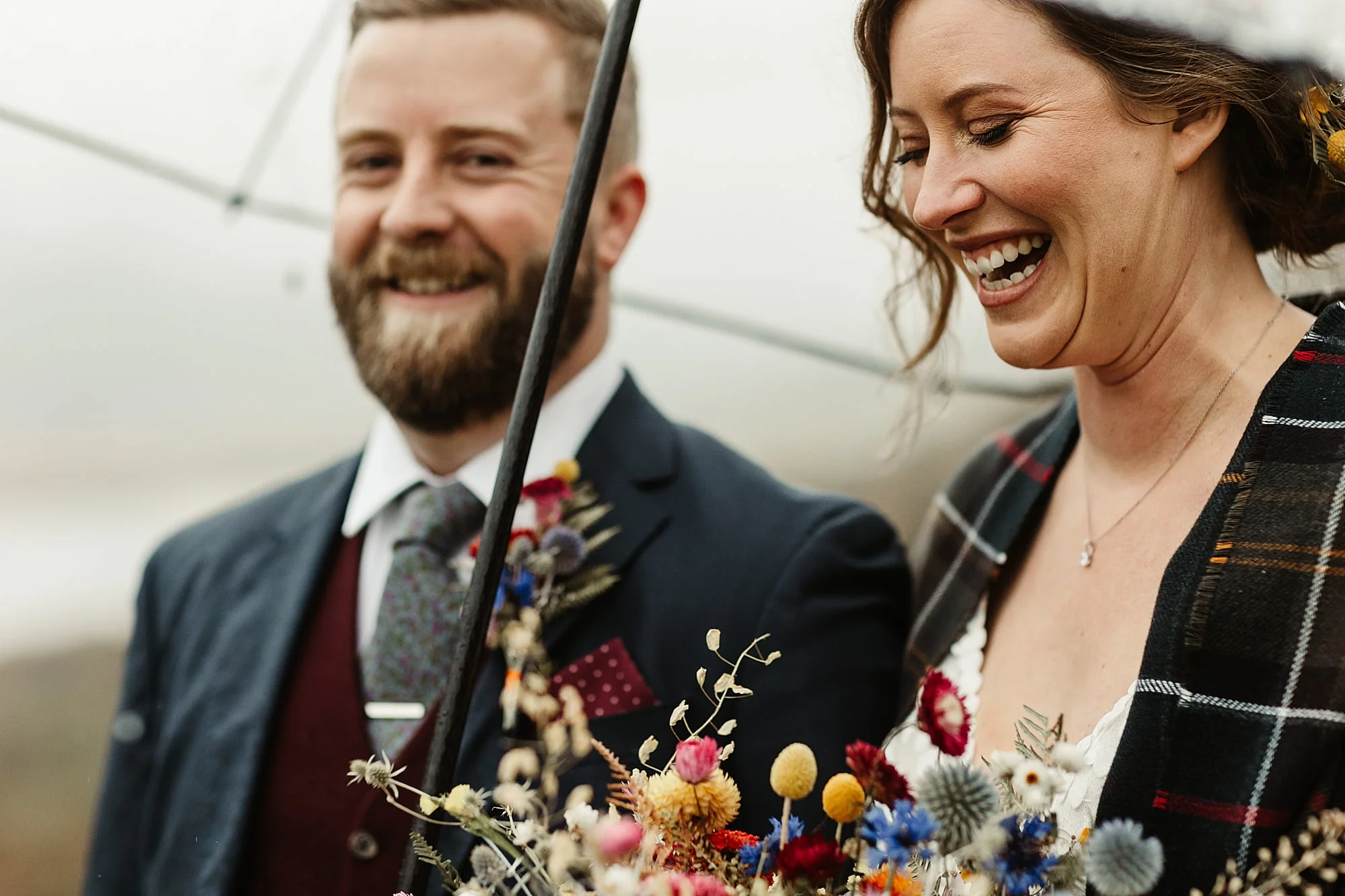 monachyle mhor ceremony outside elopement in the rain with umbrella bride and groom tartan blanket
