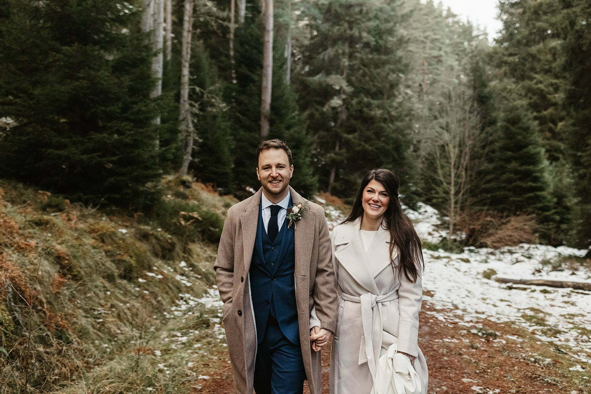 Cairngorms national park snowy tree lined path bride groom walking