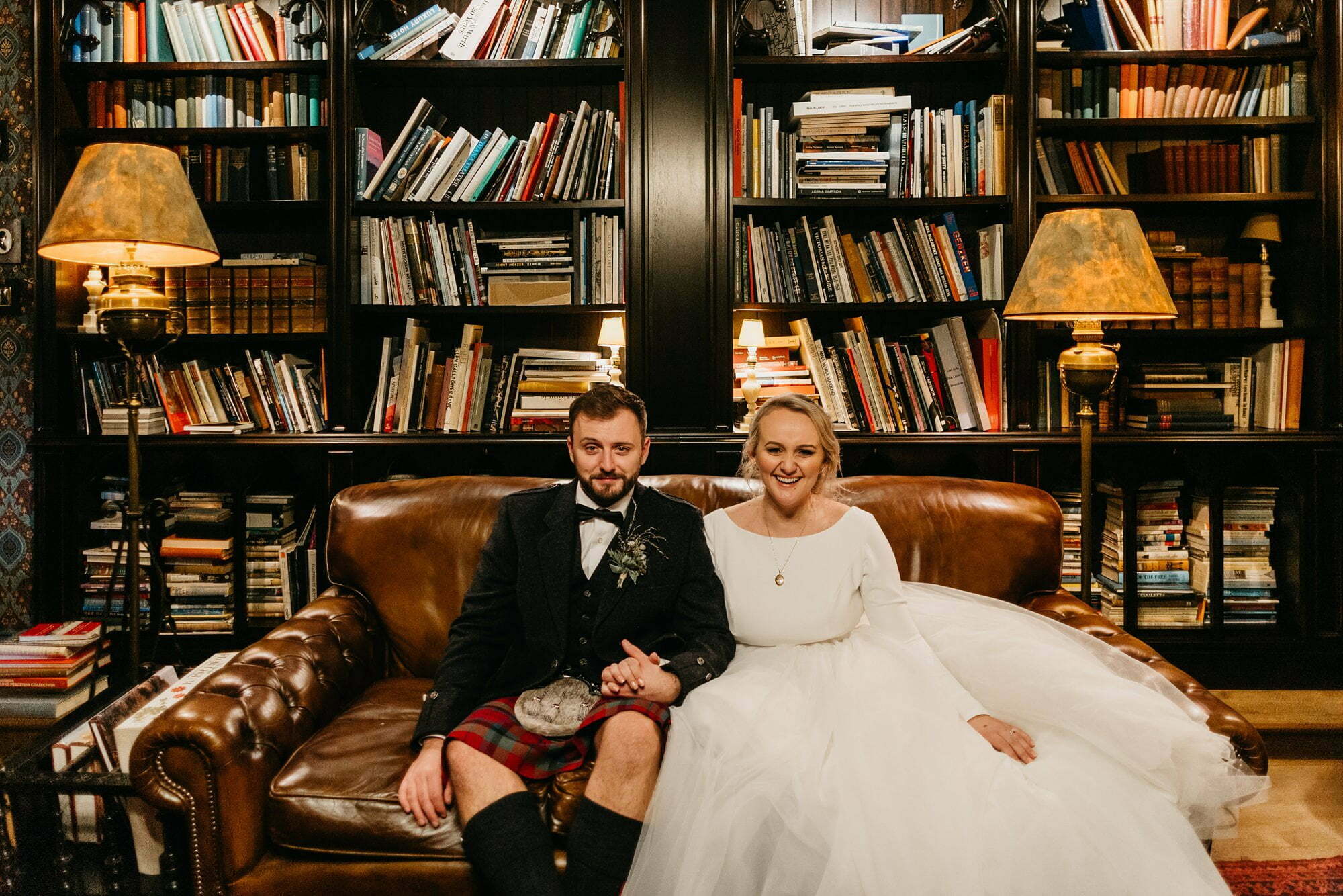 fife arms hotel braemar wedding portraits bride groom library sitting on chesterfield couch smiling