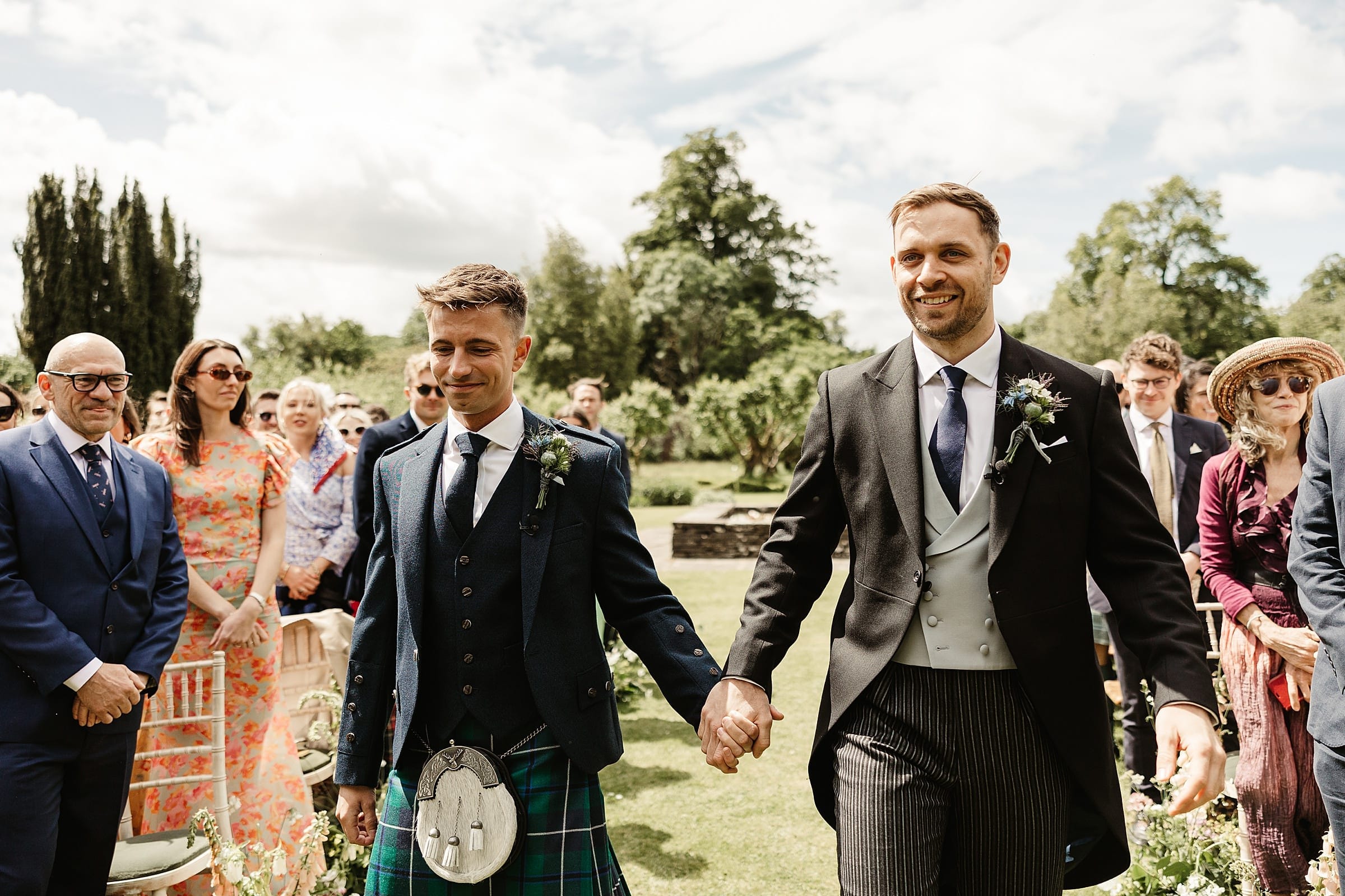 two grooms walking down the aisle together byre at inchyra outdoor ceremony